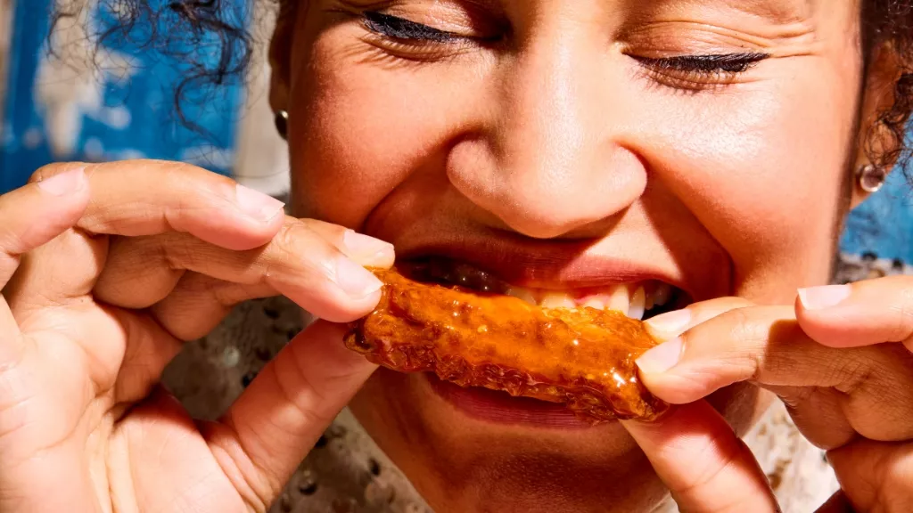 woman biting into chicken wing