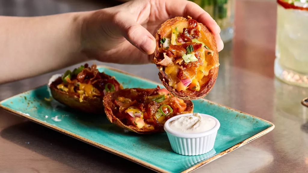 Loaded potato skins being dipped into sauce