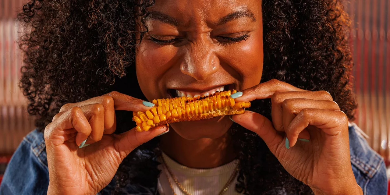 Woman biting into corn