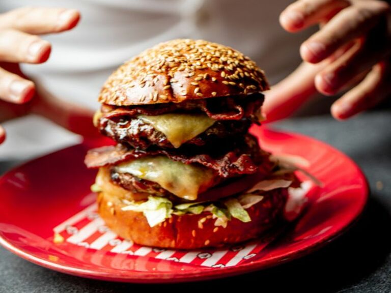 TGI burger on plate with hands about to grab it